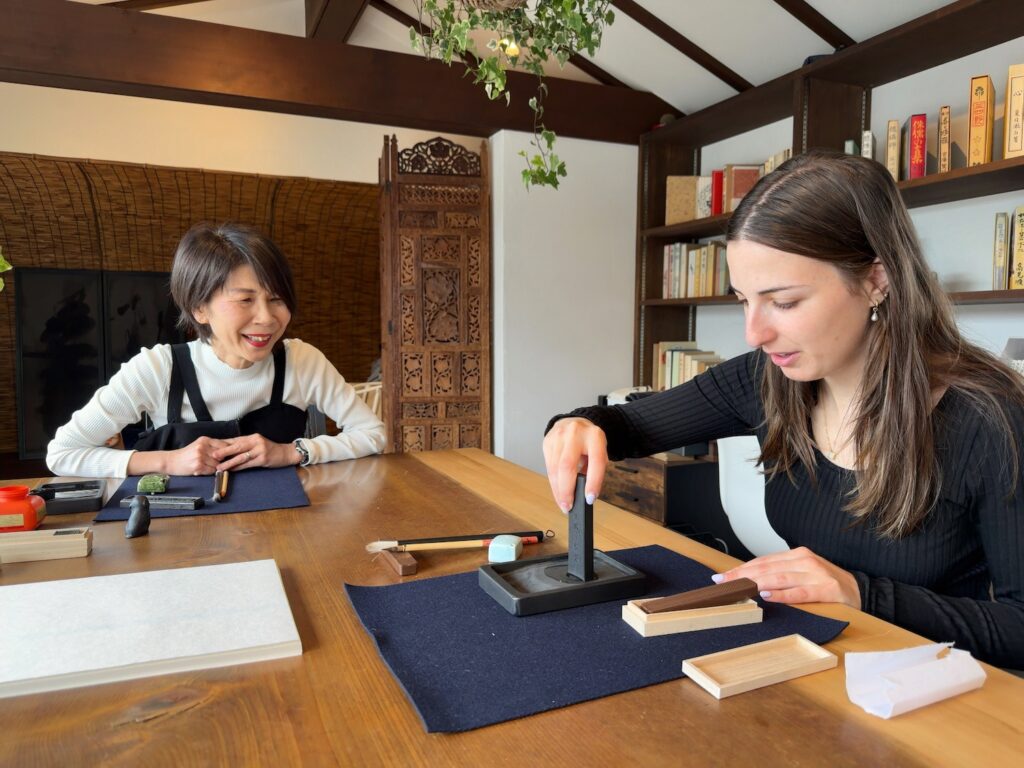 Guest from the United States grinding ink stick during a Japanese calligraphy experience at Atelier & Gallery Ichirin in Kamakura