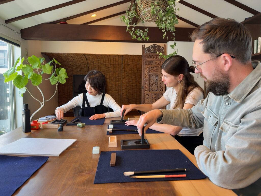 Two guests from Germany grinding sumi ink during a Japanese calligraphy experience at Atelier & Gallery Ichirin in Kamakura