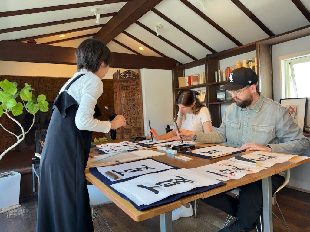 Two guests from Germany practicing kanji writing during a meditative calligraphy experience in Kamakura