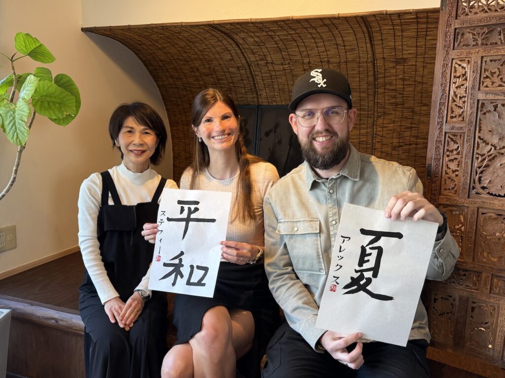 Instructor and two guests from Germany holding completed Japanese calligraphy artwork at Atelier & Gallery Ichirin in Kamakura
