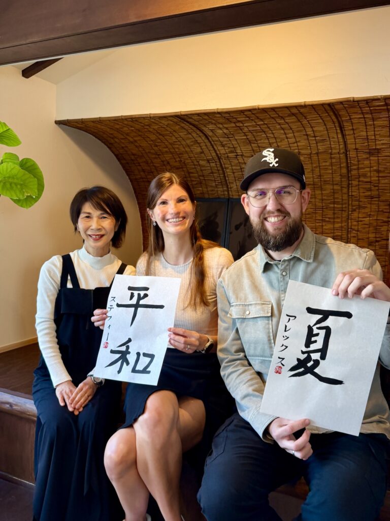 Instructor and two guests from Germany holding completed Japanese calligraphy artwork at Atelier & Gallery Ichirin in Kamakura