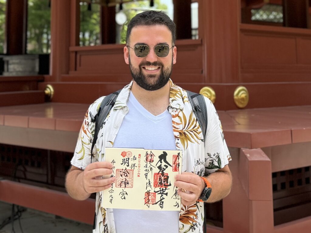 A guest from Spain holding goshuin stamps at Tsurugaoka Hachimangu Shrine in Kamakura