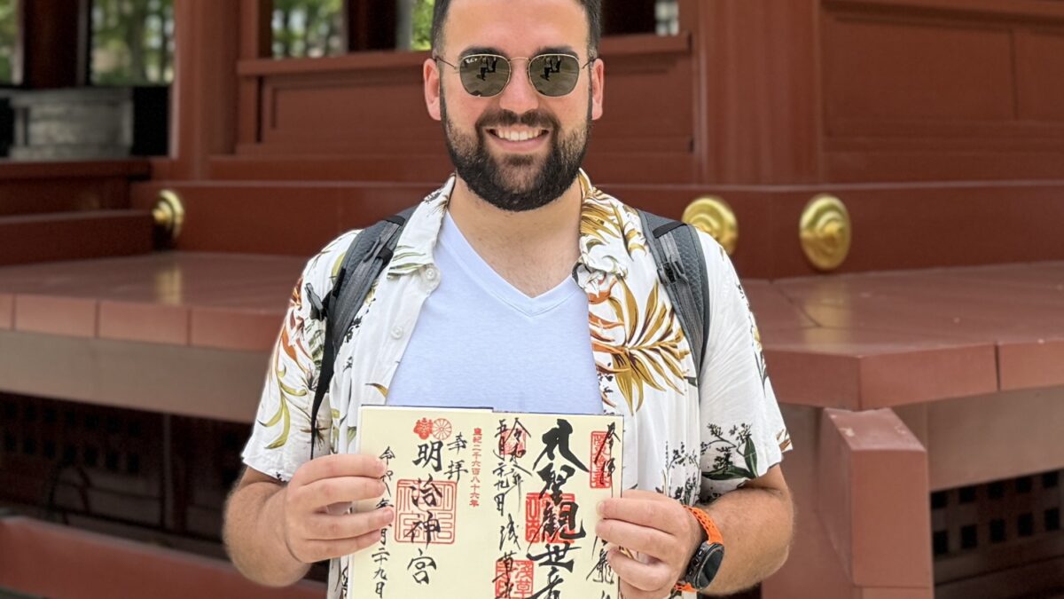 A guest from Spain holding goshuin stamps at Tsurugaoka Hachimangu Shrine in Kamakura