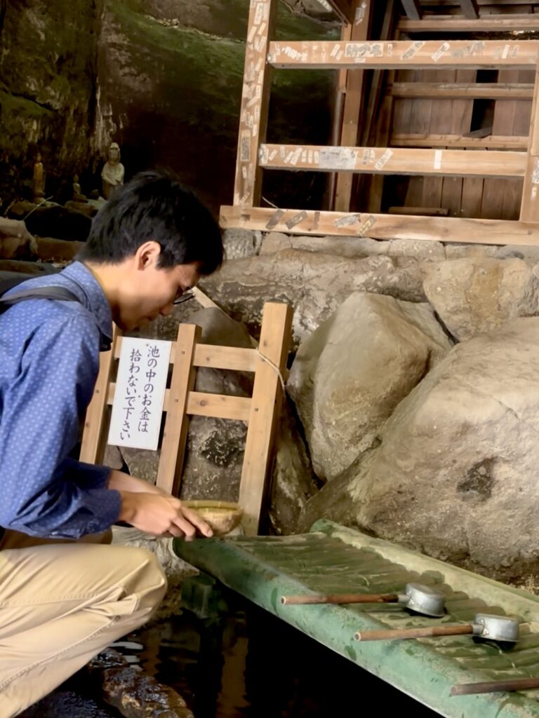 Shaking off water from washed money at Zeniarai Benzaiten