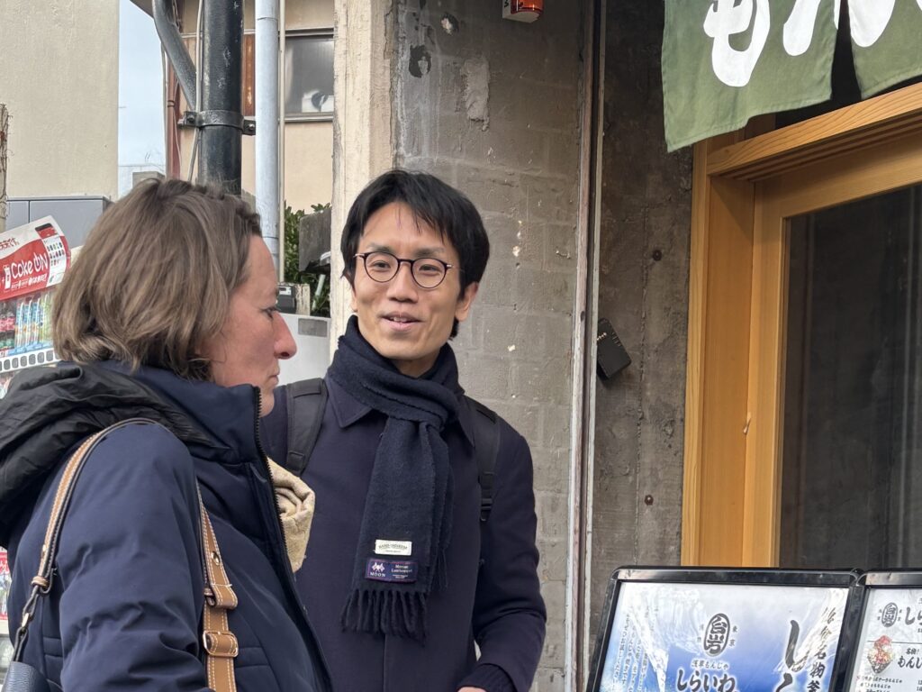 Local guide explaining in front of a monja restaurant to guests during a private tour in Kamakura